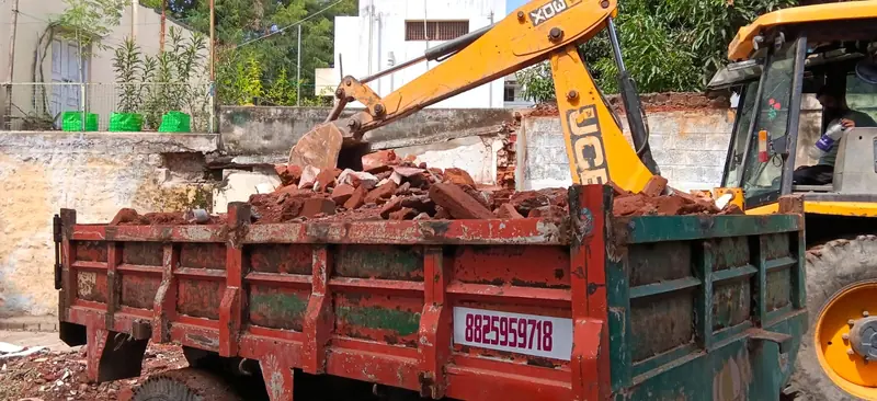 JCB loading brick rubble into a tractor trailer in Coimbatore
