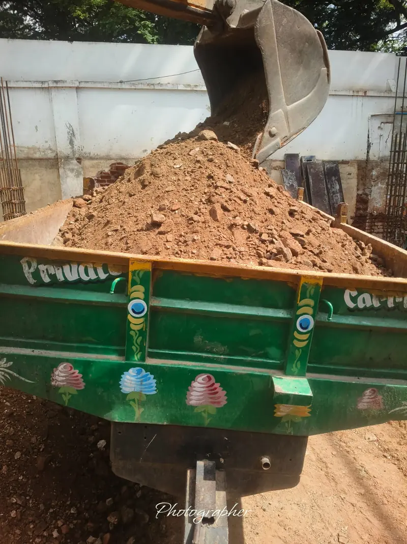 Excavator loading soil into a tractor trailer in Coimbatore